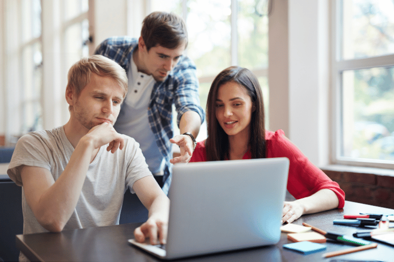 Students discussing and reviewing a real estate exam prep course on a laptop