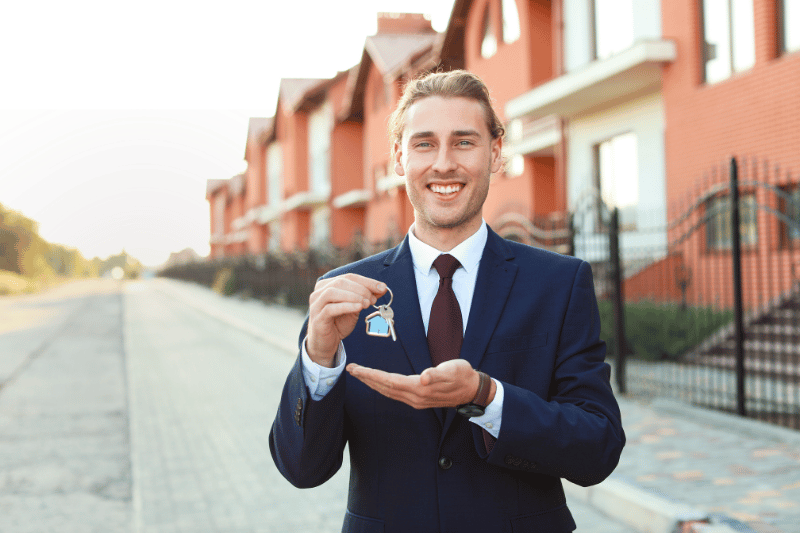 Smiling real estate agent holding house keys, symbolizing success.