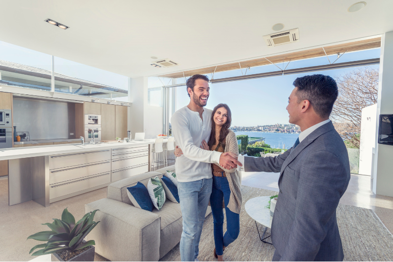 Real estate agent successfully negotiating a home purchase with smiling couple inside a modern home – GSREA